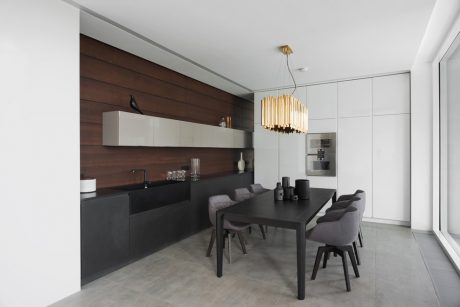 Sleek, modern kitchen with dark wood paneling, streamlined cabinets, and a statement chandelier.