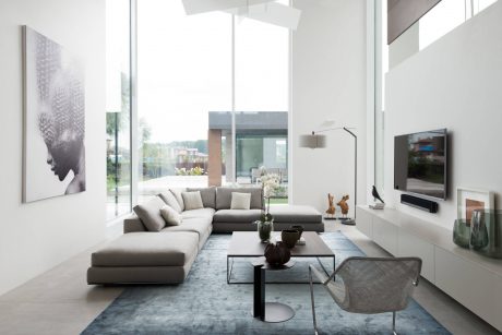 Sleek, modern living room with large windows, plush gray sofa, and minimalist decor.