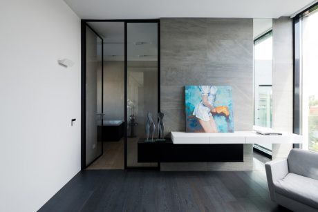 Sleek, minimalist interior with glass-paneled doorway, floating cabinet, and vibrant artwork.