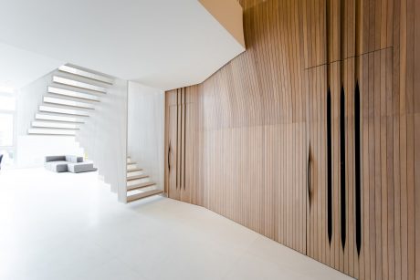 Minimalist staircase and wood paneled wall in a bright, modern interior design.