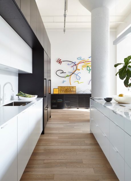 Sleek, modern kitchen with minimalist cabinetry, marble countertops, and a vibrant abstract wall art.