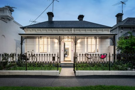 A historic building with ornate architectural details, including a decorative porch and iron fencing.
