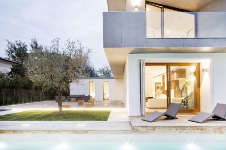Modern, minimalist home with sleek outdoor patio, pool, and lush landscaping.