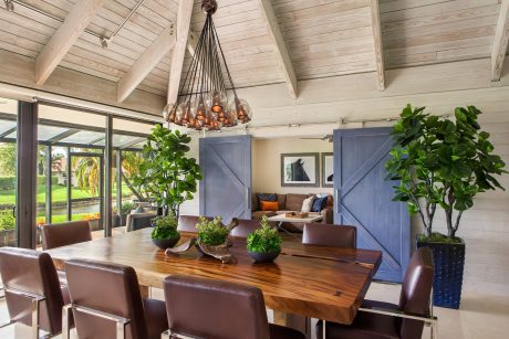 Rustic dining room with vaulted wooden ceiling, large chandelier, and sliding barn doors.