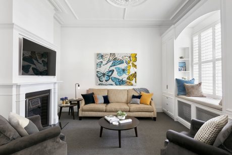 Well-appointed living room with white walls, decorative molding, and butterfly artwork.