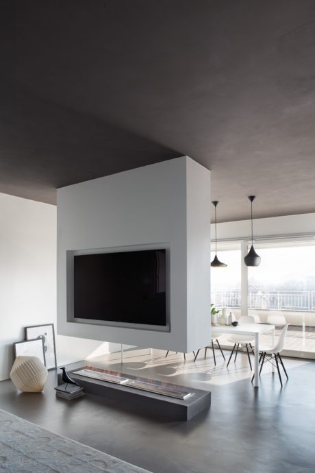 Minimalist living room with large TV, pendant lights, and modern dining furniture.