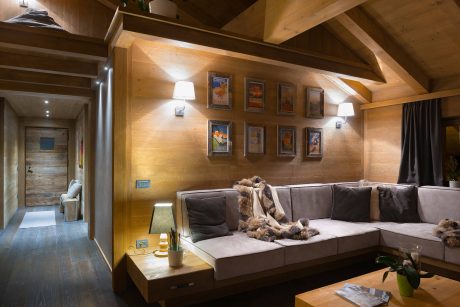Cozy chalet interior with exposed wooden beams, plush seating, and framed artwork.