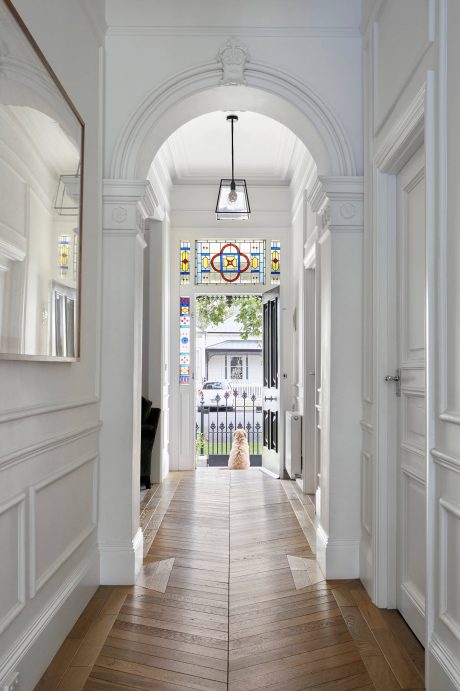 Elegant arched entryway with ornate molding and stained glass accents leads to exterior.