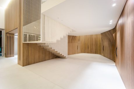 Spacious, modern interior with a striking wooden staircase and clean, minimalist design.