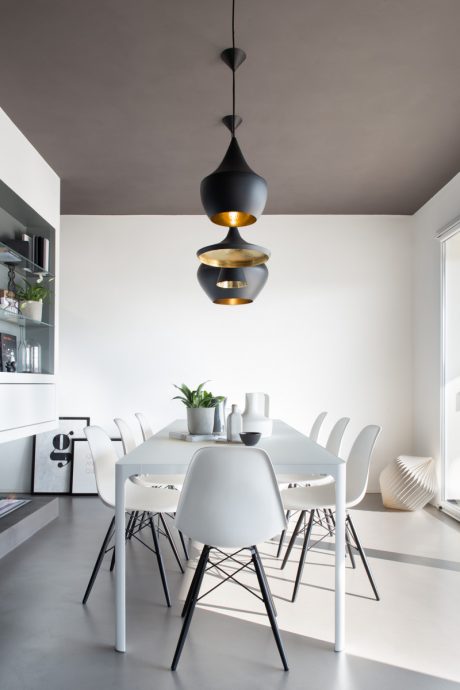 Modern dining space with sleek minimalist furniture, black and gold pendant lights.