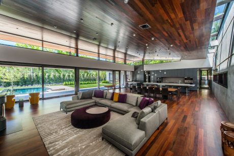 Spacious modern interior with wooden ceiling, large windows, and a cozy sectional sofa.