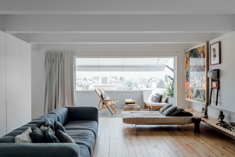 Spacious living room with large windows, modern decor, and panoramic urban view.