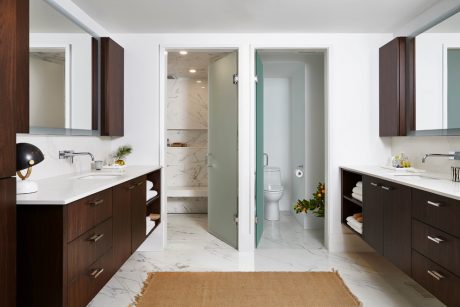Spacious, modern bathroom with marble floors, wooden vanities, and glass-enclosed shower.