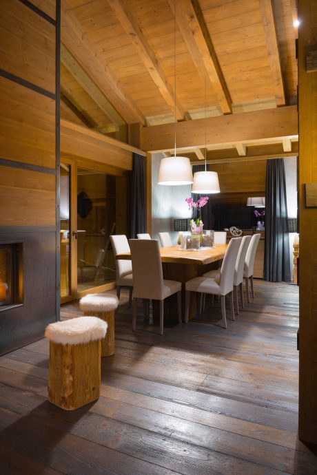A cozy, wood-paneled dining room with a contemporary light fixture and plush seating.