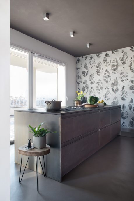 Modern kitchen with sleek dark cabinets, patterned wall, and minimalist decor.