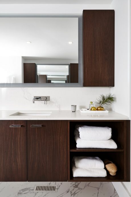 Modern bathroom vanity with dark wood cabinetry, white countertop, and built-in storage.