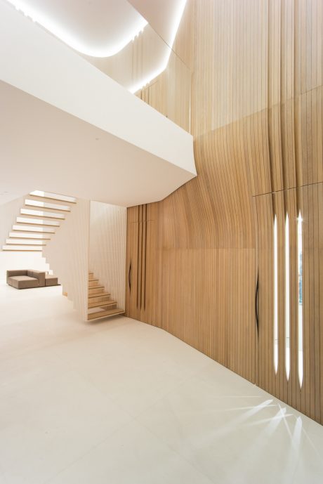 Minimalist interior with wooden paneled walls, floating staircase, and recessed lighting.