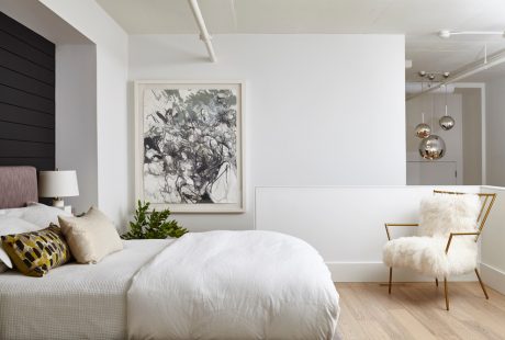 Elegant modern bedroom with abstract artwork, plush furnishings, and contemporary lighting.