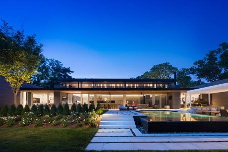 Stunning modern single-story home with large patio, pool, and lush landscaping.