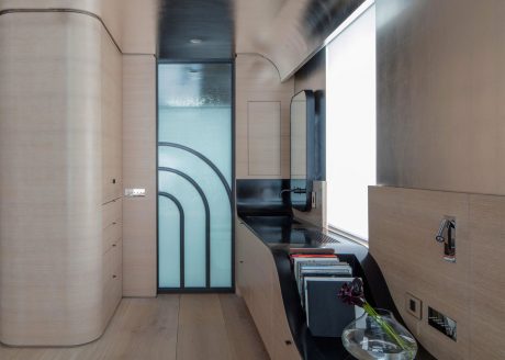 Modern minimalist interior with curved glass walls, built-in storage, and recessed lighting.