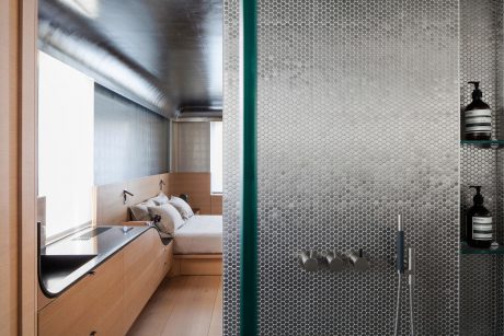 Modern minimalist bathroom with hexagonal tile walls, recessed lighting, and built-in vanity.