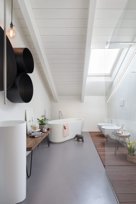 Minimalist white bathroom with wooden elements, modern fixtures, and bright natural lighting.