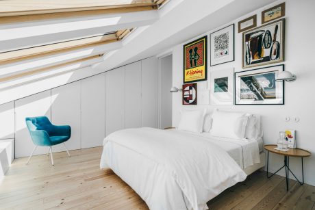 Bright, modern bedroom with wood paneling, angled ceilings, and artful wall decor.