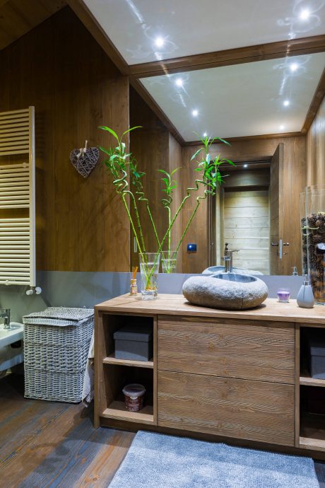 Rustic bathroom with wooden walls, recessed lighting, and a natural stone sink basin.