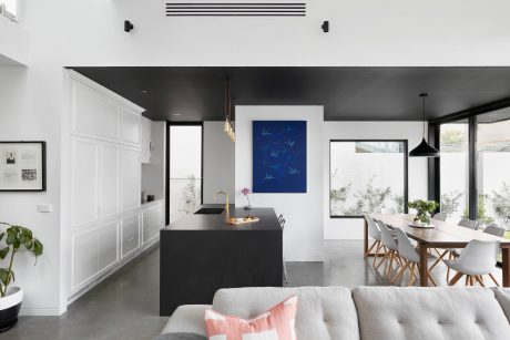 A modern, minimalist interior with sleek black and white design elements, including a black kitchen island and dining area.