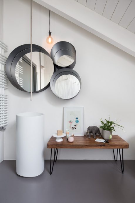 Modern entryway with round mirrors, pendant lights, wooden table, and decorative elements.
