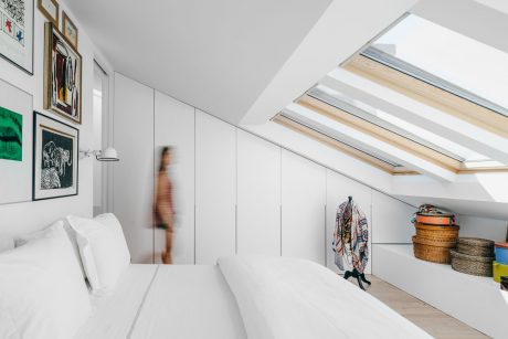 Bright, modern loft bedroom with skylights, built-in cabinetry, and eclectic decor.