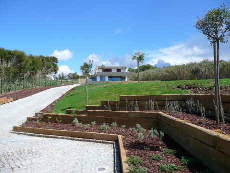 Stunning landscaped garden with multilevel terraces, lush greenery, and a modern building.