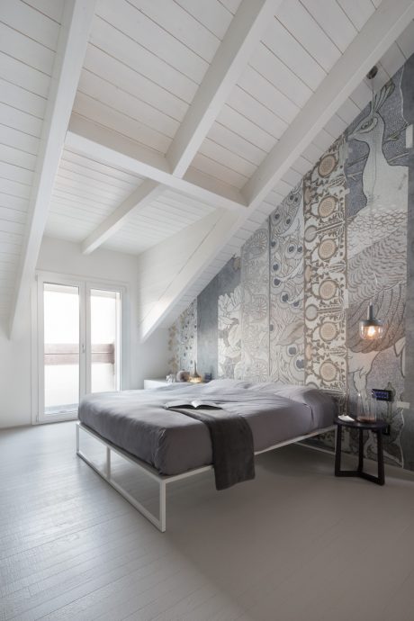 Minimalist bedroom with patterned accent wall, vaulted ceiling, and modern furnishings.