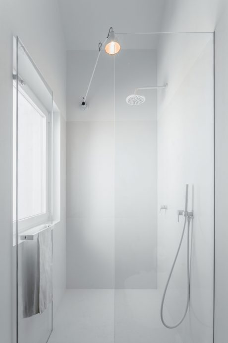 A modern, minimalist bathroom with a glass shower enclosure and a sleek wall-mounted showerhead.