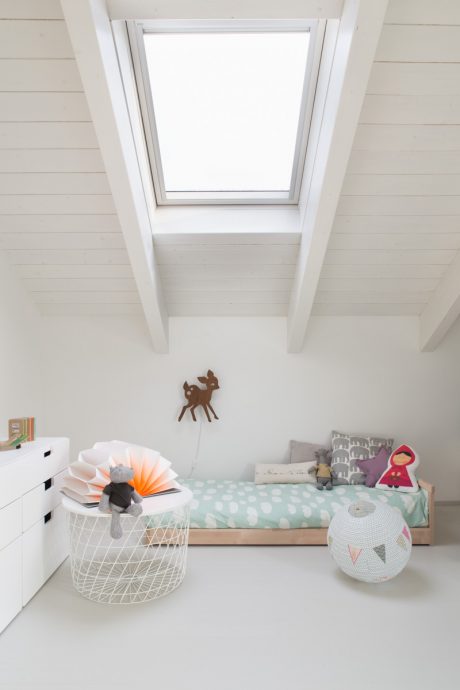 Bright, minimalist children's bedroom with a skylight, white walls, and modern furnishings.