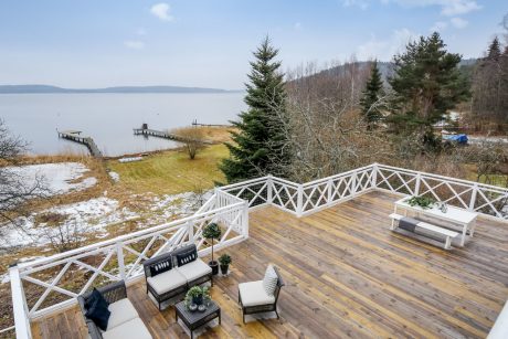 Expansive wooden deck with trellised railings overlooking a waterfront cove.