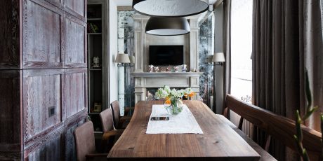 Rustic wooden walls, ornate fireplace mantel, and modern lighting fixtures create a cozy, elegant space.