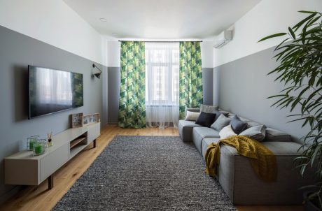 A cozy and stylish living room with patterned curtains, plush furniture, and a large TV.