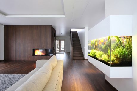 Minimalist living room with dark wood paneling, fireplace, and large aquarium feature.