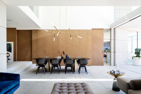 Modern, minimalist dining area with wood paneling, sculptural light fixture, and plush furniture.
