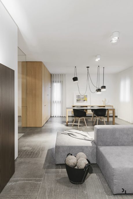 Minimalist living room with wood furniture, pendant lights, and textured grey sofa.