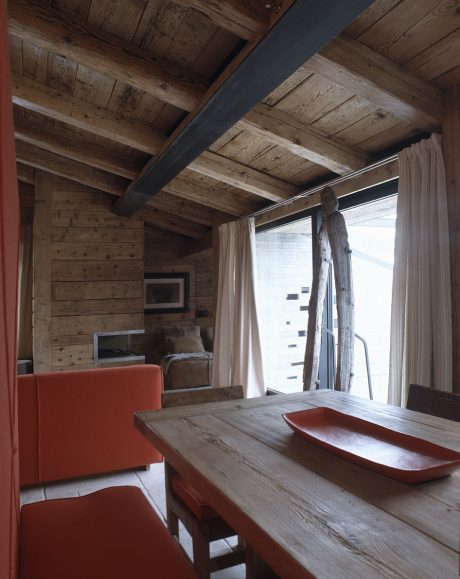 Rustic wooden cabin interior with modern furniture and large windows showcasing nature.
