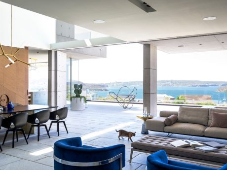 Modern, open-plan living space with panoramic water views, sleek furnishings, and sculptural lighting.