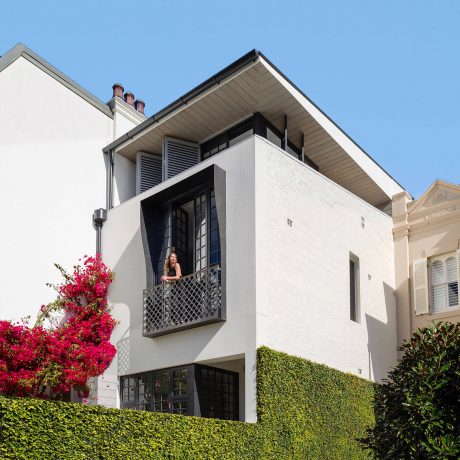 Striking architecture with intricate balcony design, surrounded by verdant foliage.