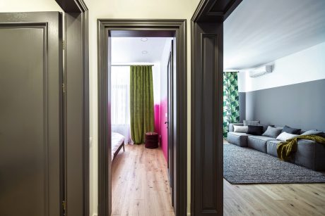 Spacious modern apartment with wooden floors, gray sofa, and green curtains.
