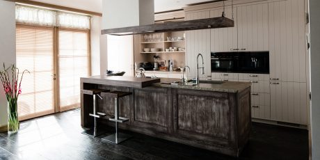 Rustic kitchen with exposed wooden beam, dark wooden cabinets, and granite countertops.