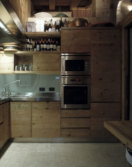 A cozy, rustic kitchen with wooden cabinetry, open shelving, and stainless steel appliances.