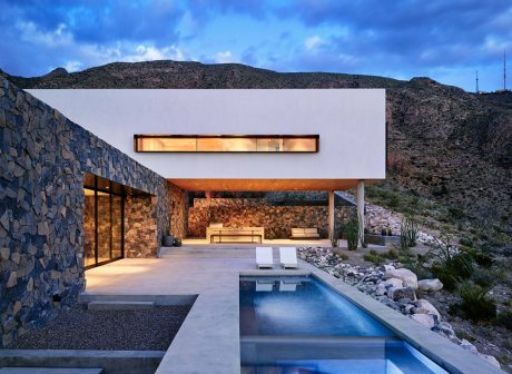 Stunning modern desert home with sleek architecture, pool, and stone walls.