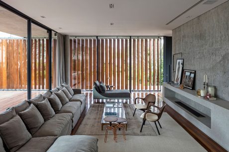 Minimalist living room with large windows, wooden slats, and modern furnishings.