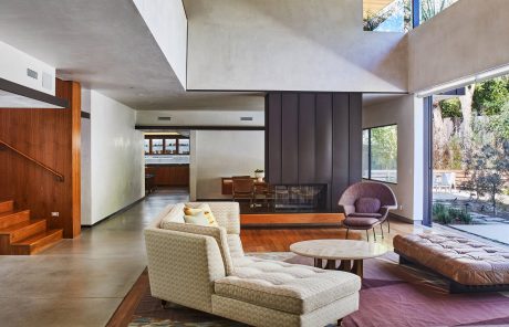 Spacious, modern living room with high ceilings, large fireplace, and mix of wood and concrete.